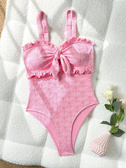 Pink textured one-piece swimsuit with ruffled trim and adjustable straps