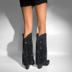 Black fringe boots with rhinestones worn by a person on a gray background