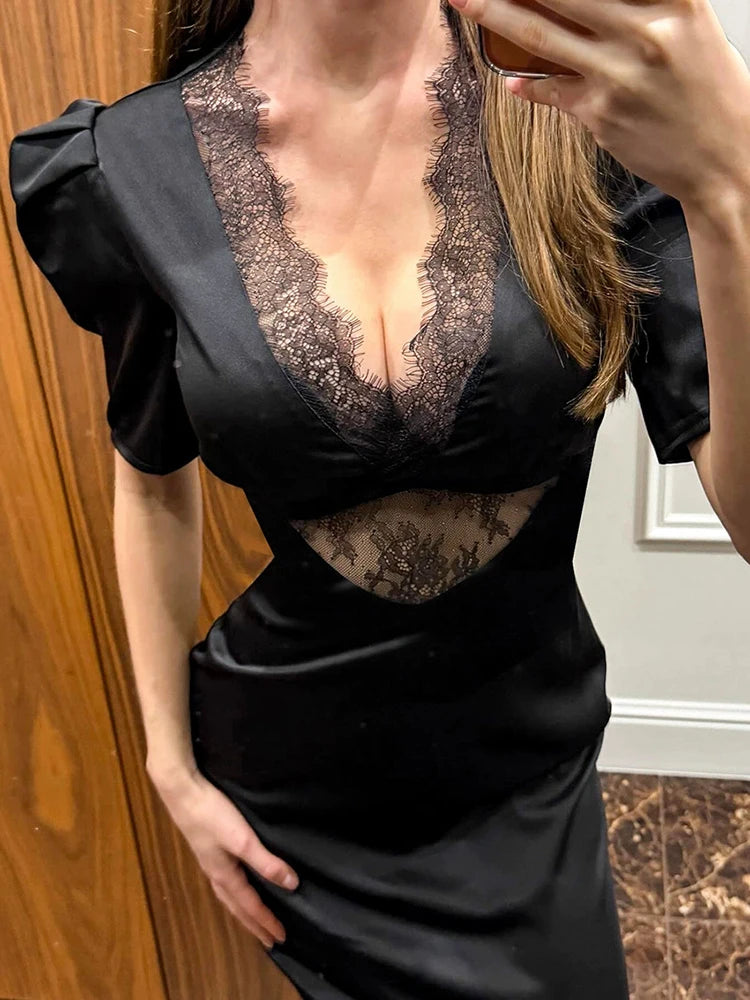 Person wearing a black dress with lace detailing in front of a wooden door.