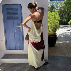 Woman in a white and red dress standing outdoors with a blue door and greenery in the background