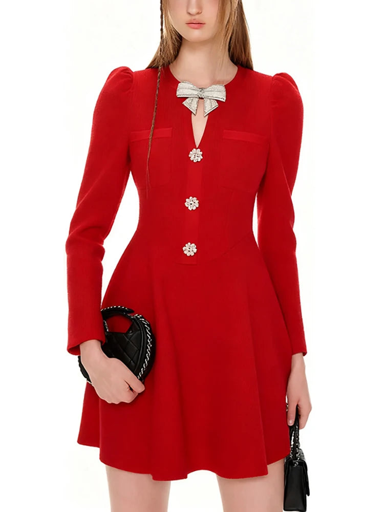 Red dress with decorative buttons and a bow, held by a person