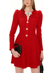 Red dress with decorative buttons and a bow, held by a person