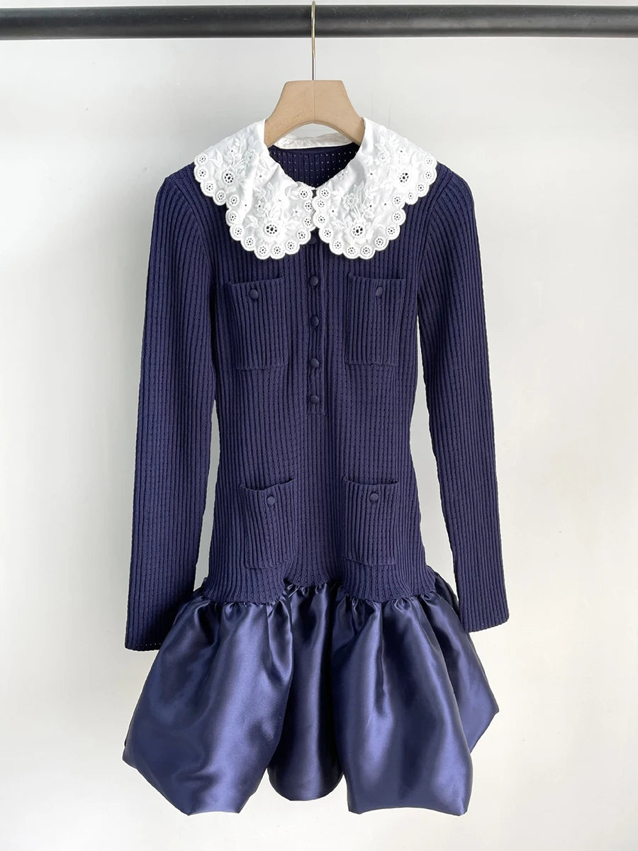 Navy blue dress with white lace collar on a hanger against a white background