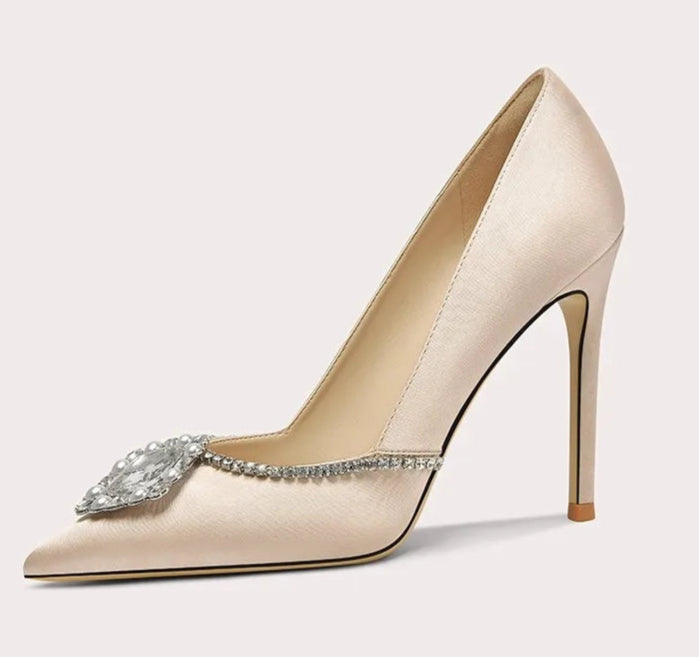 Beige high-heeled shoe with decorative element on a light gray background