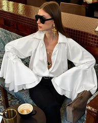 Woman in a white blouse sitting at a table in a restaurant.