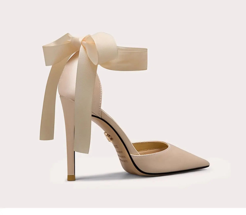 Beige high-heeled shoe with a large bow on a light gray background