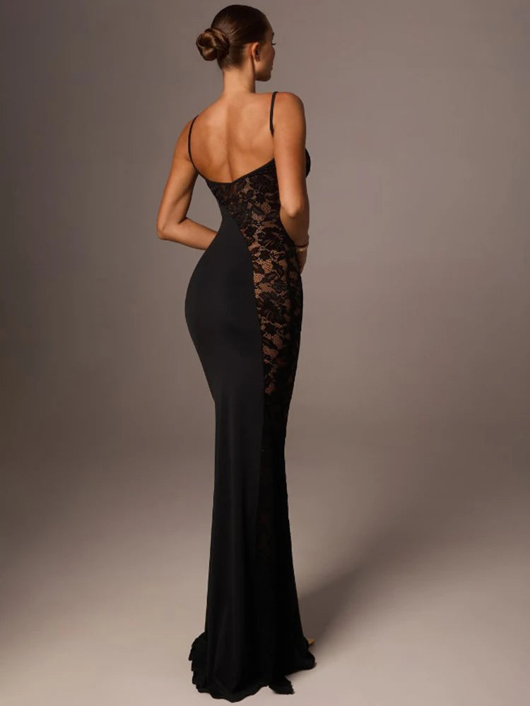 Woman wearing a black evening gown with lace detailing on a gray background