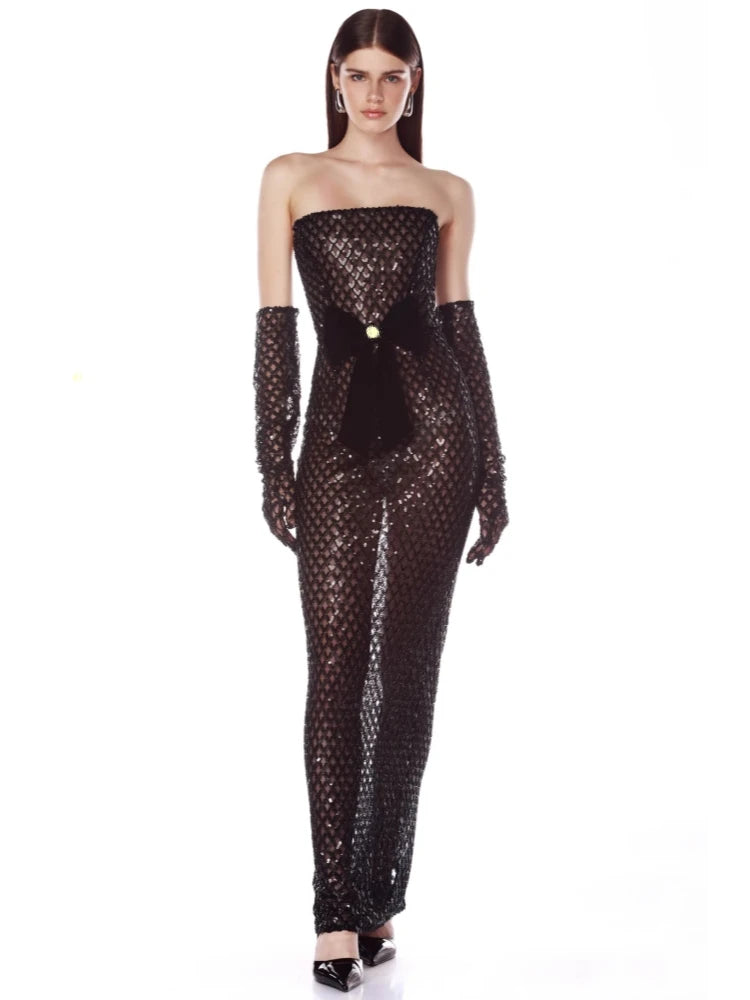 Woman wearing a black sequin jumpsuit with long gloves on a white background