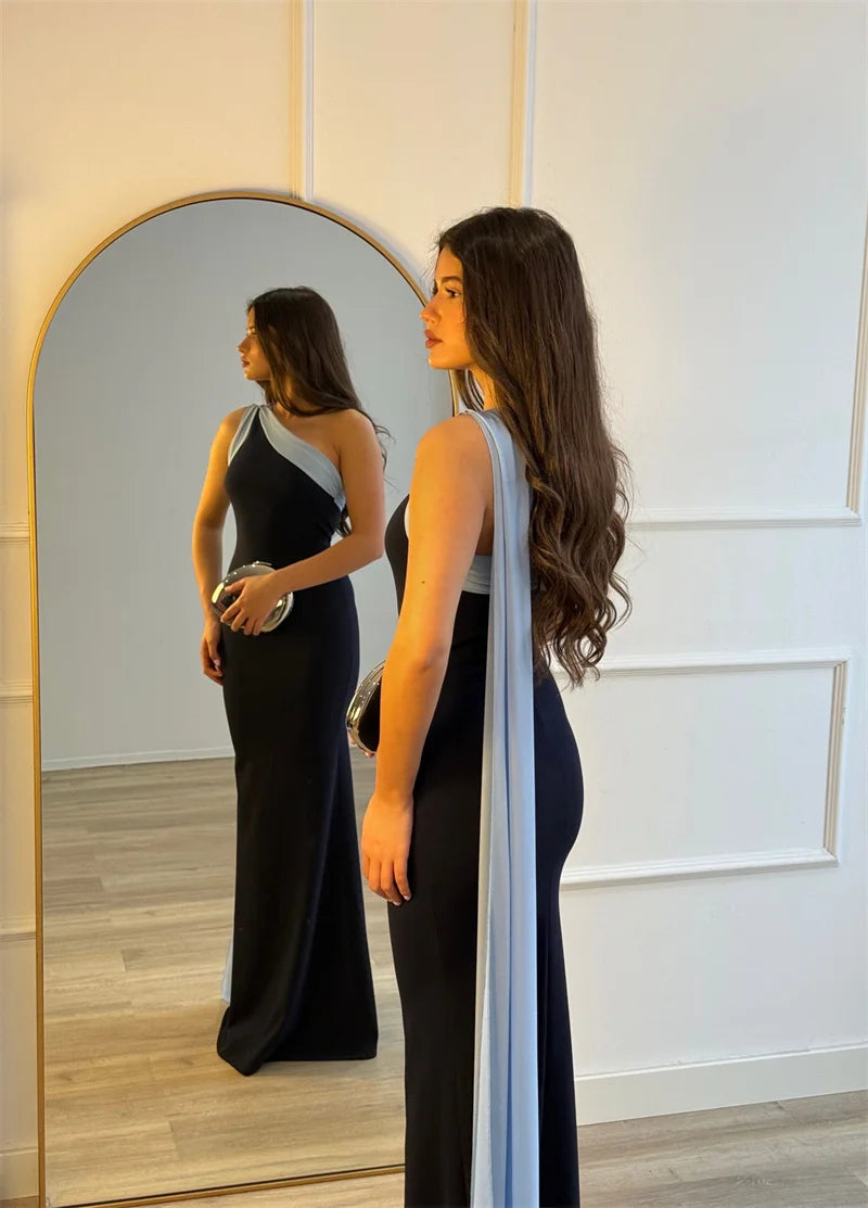 Woman in a black evening gown standing in front of a mirror.