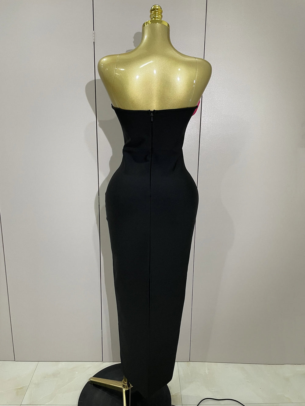 Black evening gown on a mannequin against a white wall