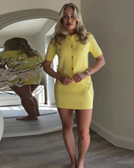Woman wearing a yellow dress standing in a room with a mirror and decorative elements.