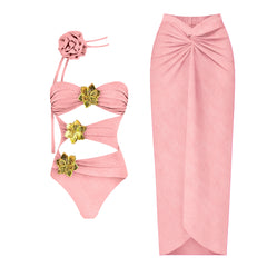 Hot pink one-piece swimsuit with cutouts and gold flower accents, paired with a matching flowing skirt.