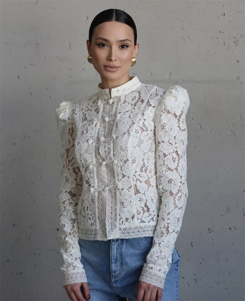 Woman wearing a white lace blouse with long sleeves against a gray background