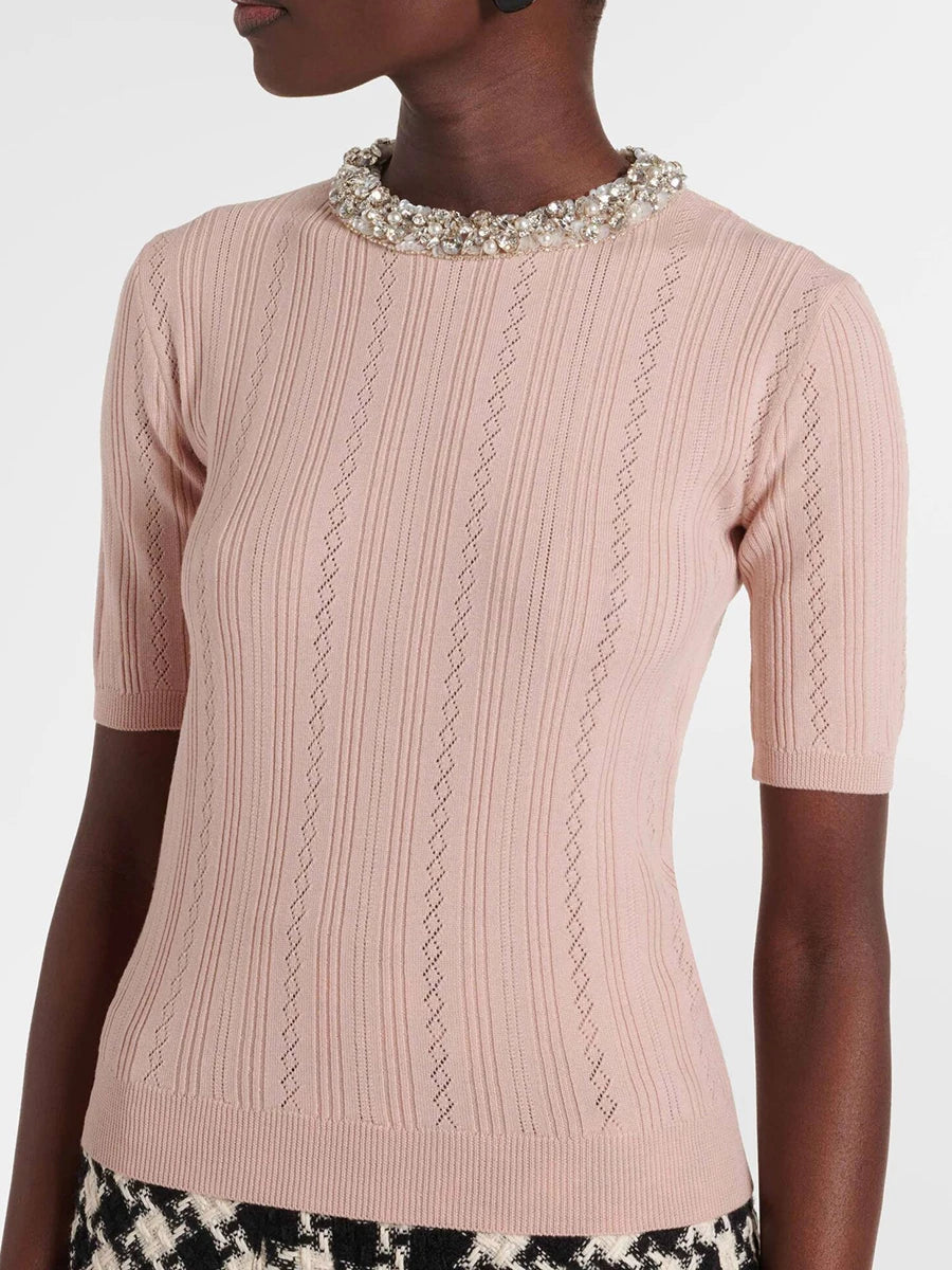 Pink ribbed sweater with decorative neckline on a white background