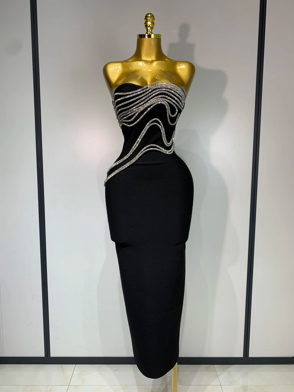 Black evening gown with silver embellishments on a mannequin against a neutral background