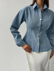 Blue denim shirt worn by a person on a plain background