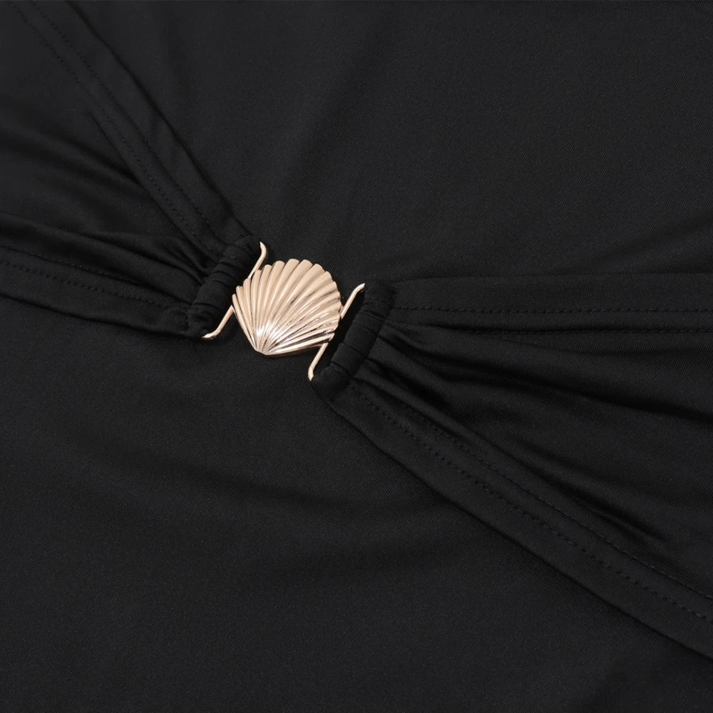 Close-up of a black garment with a gold shell brooch.