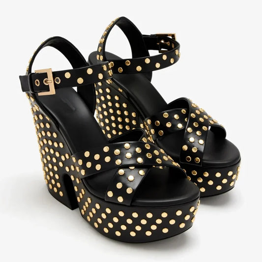 Pair of black leather platform wedge sandals with gold studs on a white background
