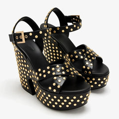 Pair of black leather platform wedge sandals with gold studs on a white background