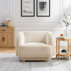 Beige armchair in a living room setting with wooden side table and abstract art on the wall.