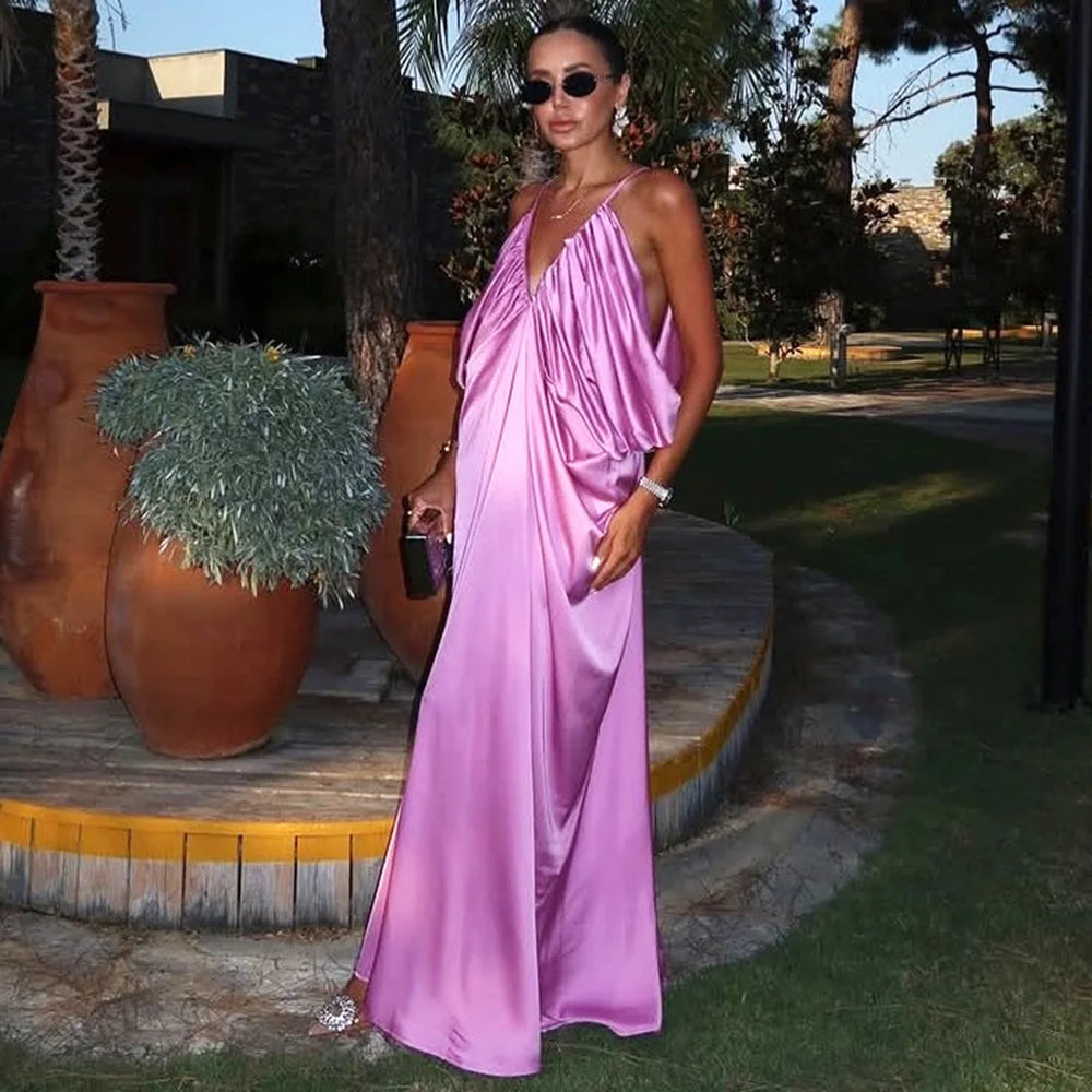 Woman in a pink dress standing outdoors with decorative pots and greenery.