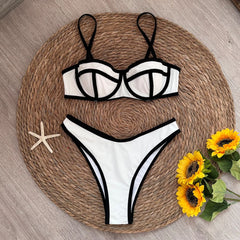 Person wearing a white bikini with black contrast trim, relaxing on a beach.