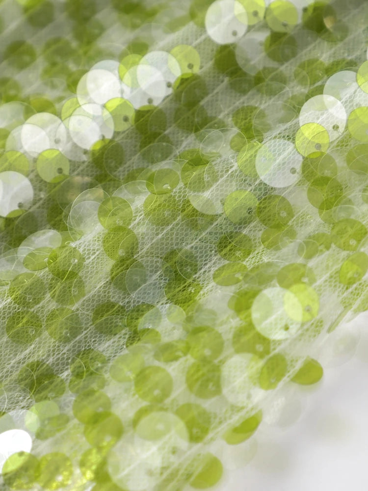 Close-up of green sequin fabric with a blurred background