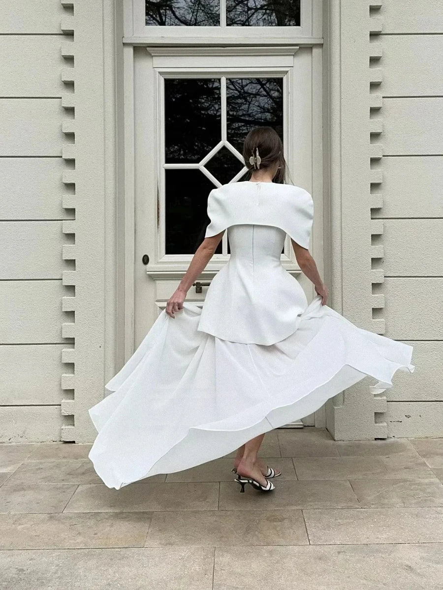Woman in a white dress standing in front of a door.