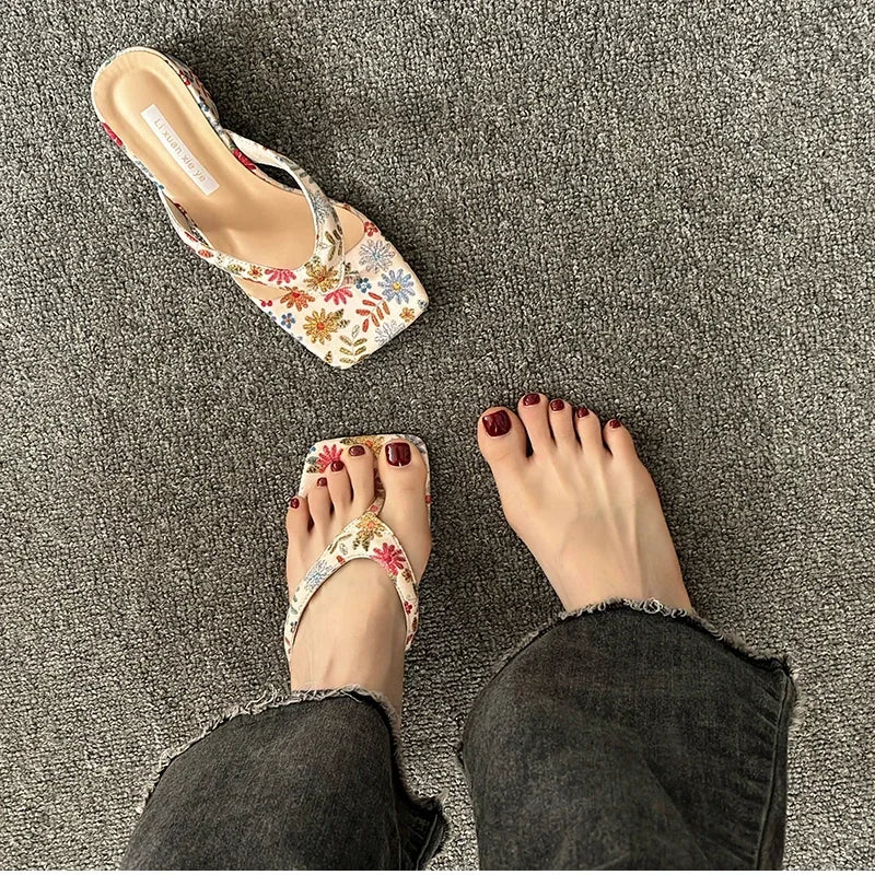 Floral sandals worn on a textured gray surface