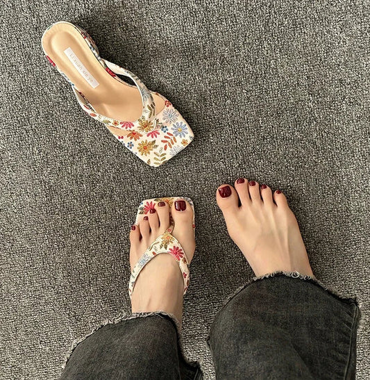 Floral sandals worn on a textured gray surface
