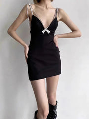 Black dress with lace details on straps worn by a person against a plain background