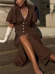 Woman in a brown dress sitting on steps with a blurred background