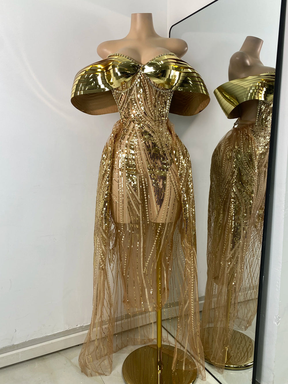 Gold sequin dress on a mannequin with a mirror reflection.