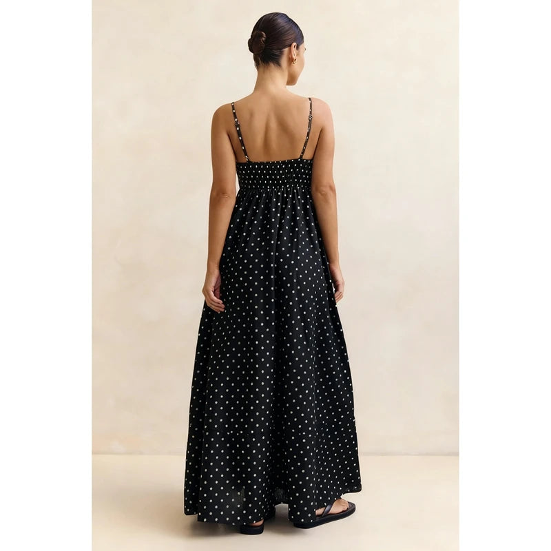 Woman wearing a black polka dot dress against a beige background