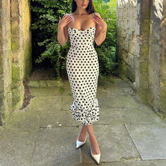 Woman wearing a polka dot dress standing in a stone-walled garden.