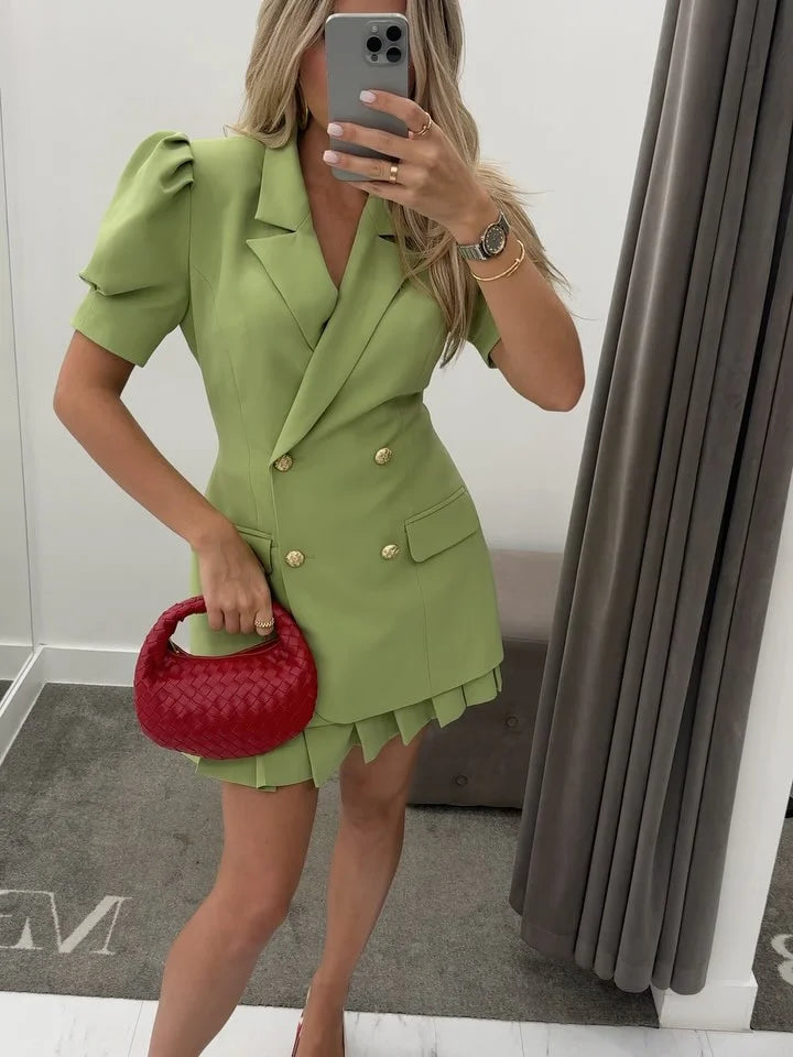 Woman taking a mirror selfie wearing a green dress with a red handbag.