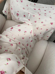 White fabric with pink floral pattern draped over a light-colored couch.