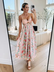 Woman taking a mirror selfie wearing a floral dress in a bright living room.