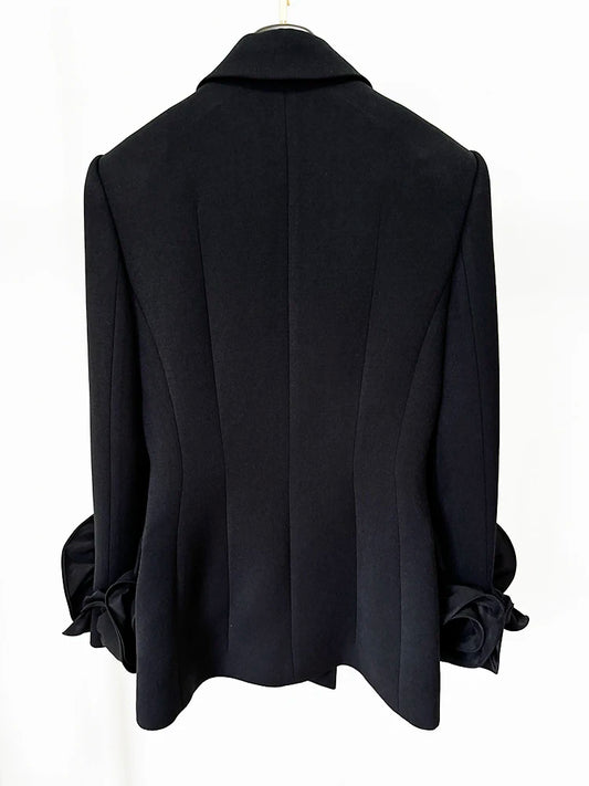 Back view of a sculpted double-breasted black blazer with floral cuff details.