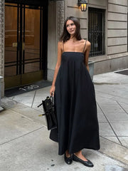 Woman in a black dress standing on a city street.