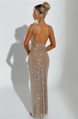 Woman wearing a sparkly gold evening gown against a plain background