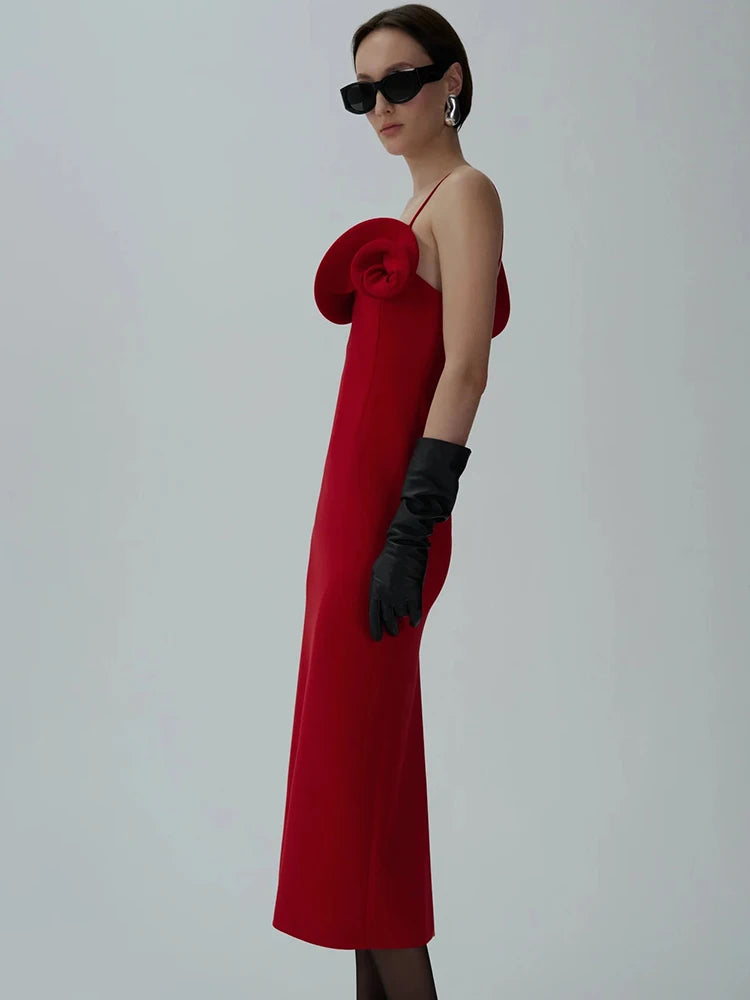 Woman wearing a red dress with a large flower detail and black gloves 