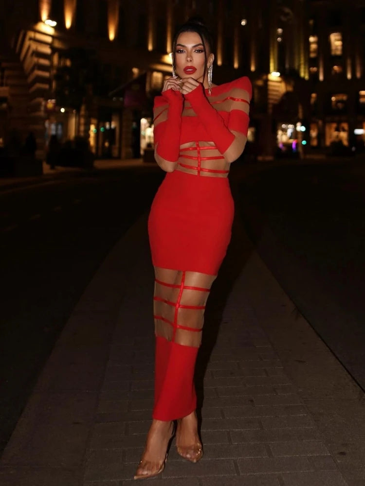 Woman in a red dress with cut-out design standing on a street at night.