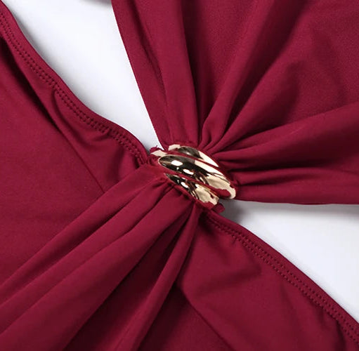 Close-up of a burgundy top with a gold ring detail on a white background