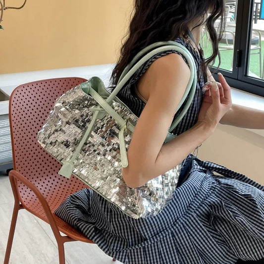 A person wearing a striped dress carries a sequin tote bag