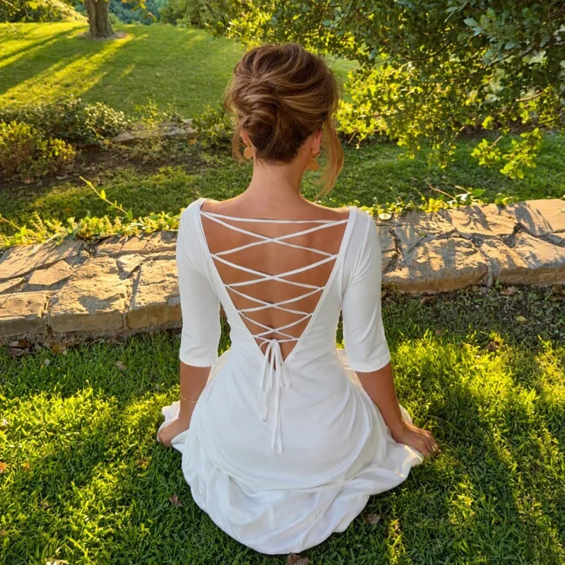 Woman wearing a white midi dress with lace-up back detail outdoors