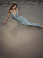 Model wearing crystal embellished V-neck maxi dress on sand