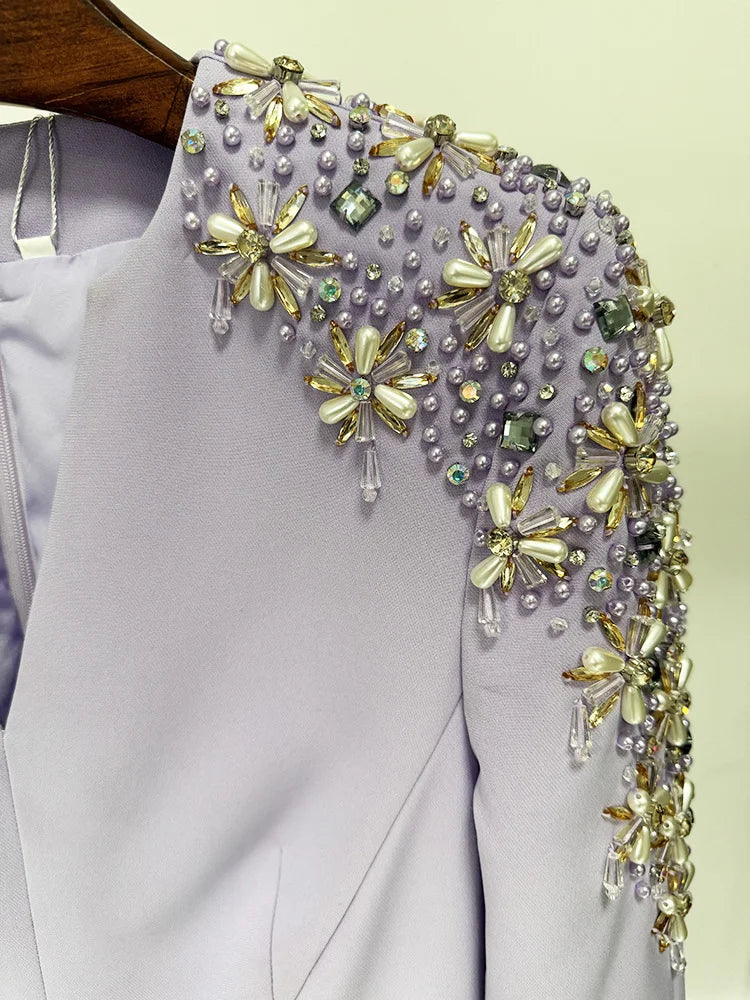 Elegant dress with floral beaded shoulder detail on a plain background