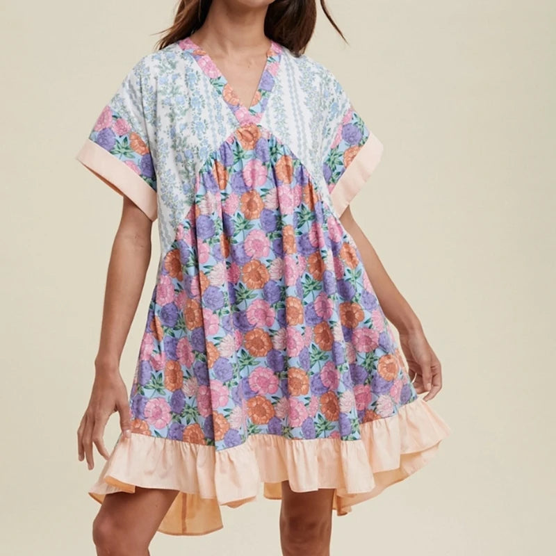 Woman in loose floral mini dress with v-neck and batwing sleeves