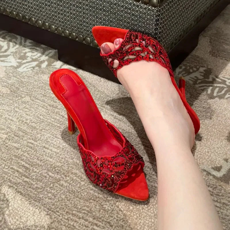 Close-up of red suede stiletto slides with crystal embellishments